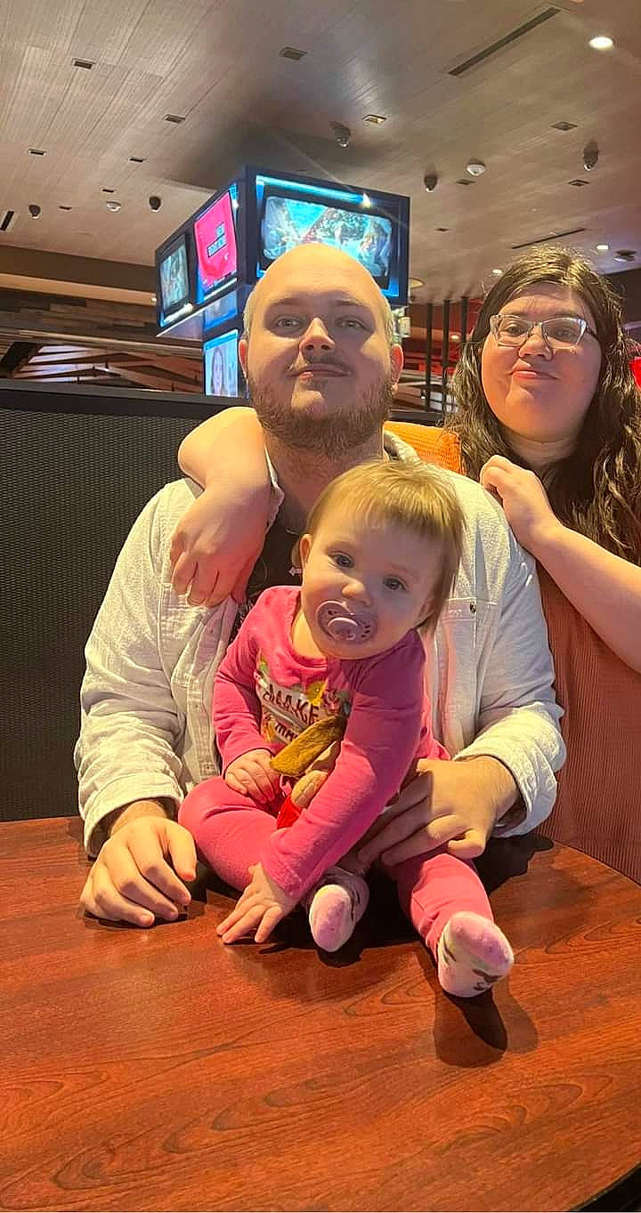 Breya is registered to the contest to win money with this photo: arm, child, event, eyewear, face, floor, flooring, fun, happy, hardwood, joy, lap, leisure, person, recreation, smile, snapshot, t_shirt, television, thumb