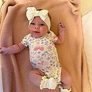 Melody joined the competition — help win amazing prizes! baby, infant, headband, bow, onesie, floral_pattern, blanket, sock, pink, cute, child, lying_down, indoors, newborn, soft_texture, small_hands, small_feet, apparel, portrait, baby_clothing