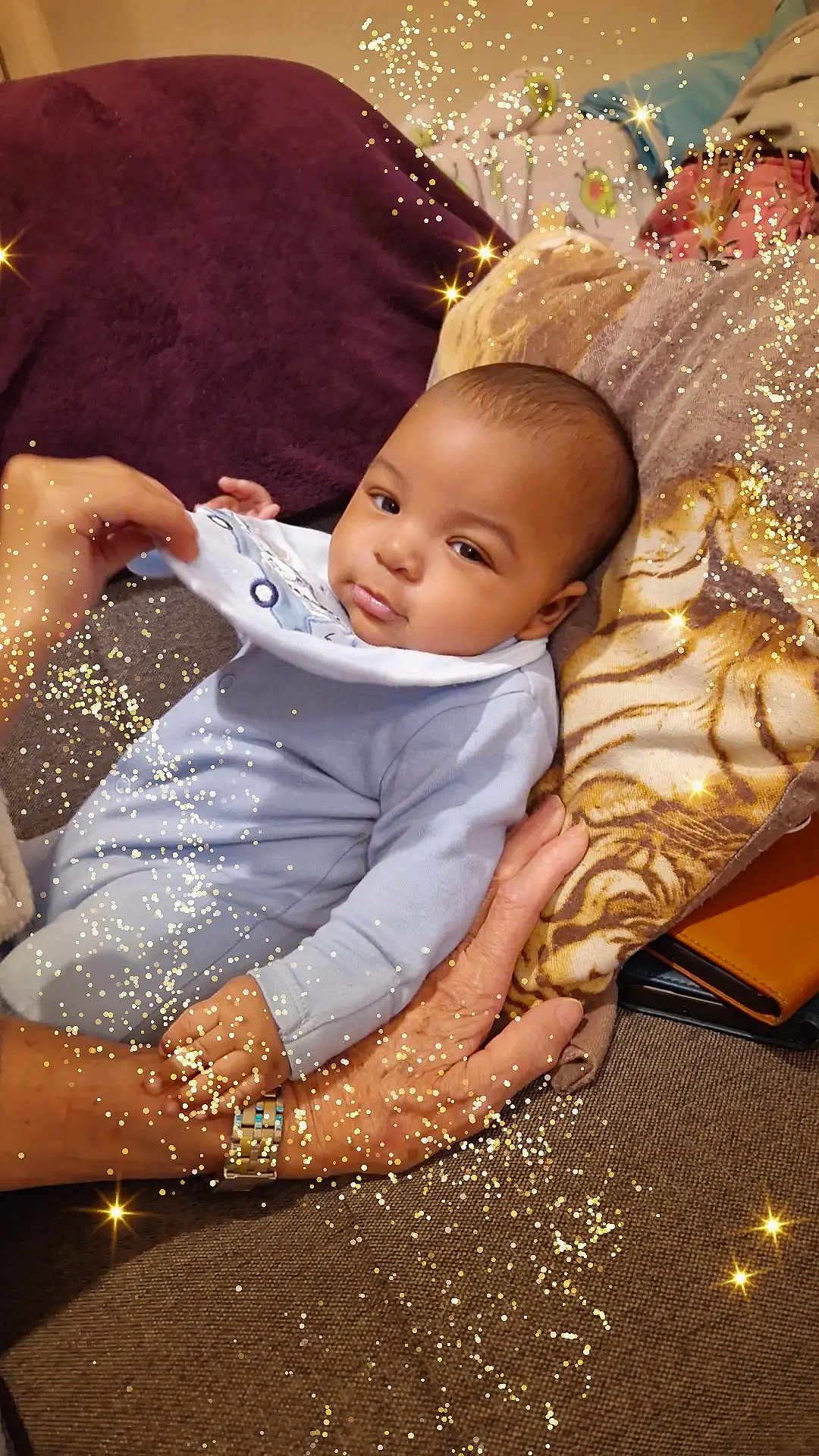 Khamis a rejoint le concours — aidez-le/la à gagner de superbes lots ! baby, infant, hand, watch, pillow, couch, blanket, onesie, face, person, sparkles, glitter, cozy, indoor, tiger_print, clothing, skin, portrait, resting, warm