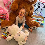 Lou a rejoint le concours — aidez-le/la à gagner de superbes lots ! toddler, child, teddy_bear, stuffed_animal, toy, playroom, piano, book, carpet, curtain, window, laughing, happy, indoor, person, plush, baby, smiling, floor, cozy