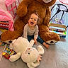 toddler, child, teddy_bear, stuffed_animal, toy, playroom, piano, book, carpet, curtain, window, laughing, happy, indoor, person, plush, baby, smiling, floor, cozy