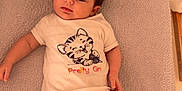 Lou participe au concours pour gagner de l'argent avec cette photo : apparel, baby, calm, changing_mat, child, cute, expression, face, floor, indoor, infant, kitten_graphic, lying_down, pants, person, striped_socks, text_on_clothing, tshirt, wooden_floor, young_child