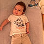 Lou participe au concours pour gagner de l'argent avec cette photo : apparel, baby, calm, changing_mat, child, cute, expression, face, floor, indoor, infant, kitten_graphic, lying_down, pants, person, striped_socks, text_on_clothing, tshirt, wooden_floor, young_child