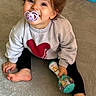 Lou a rejoint le concours — aidez-le/la à gagner de superbes lots ! baby_toy, barefoot, candid, carpet, child, colorful, curly_hair, cute, happy, heart_design, indoor, pacifier, person, playtime, rattle, smiling, sweater, toddler, toy, young_child