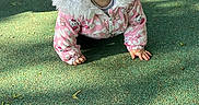 Lou participe au concours pour gagner de l'argent avec cette photo : toddler, child, crawling, playground, jacket, pink_jacket, fur_hood, curious, outdoor, daylight, play_equipment, green_surface, sunlight, shadow, baby, cute, person, young_child, park, happy