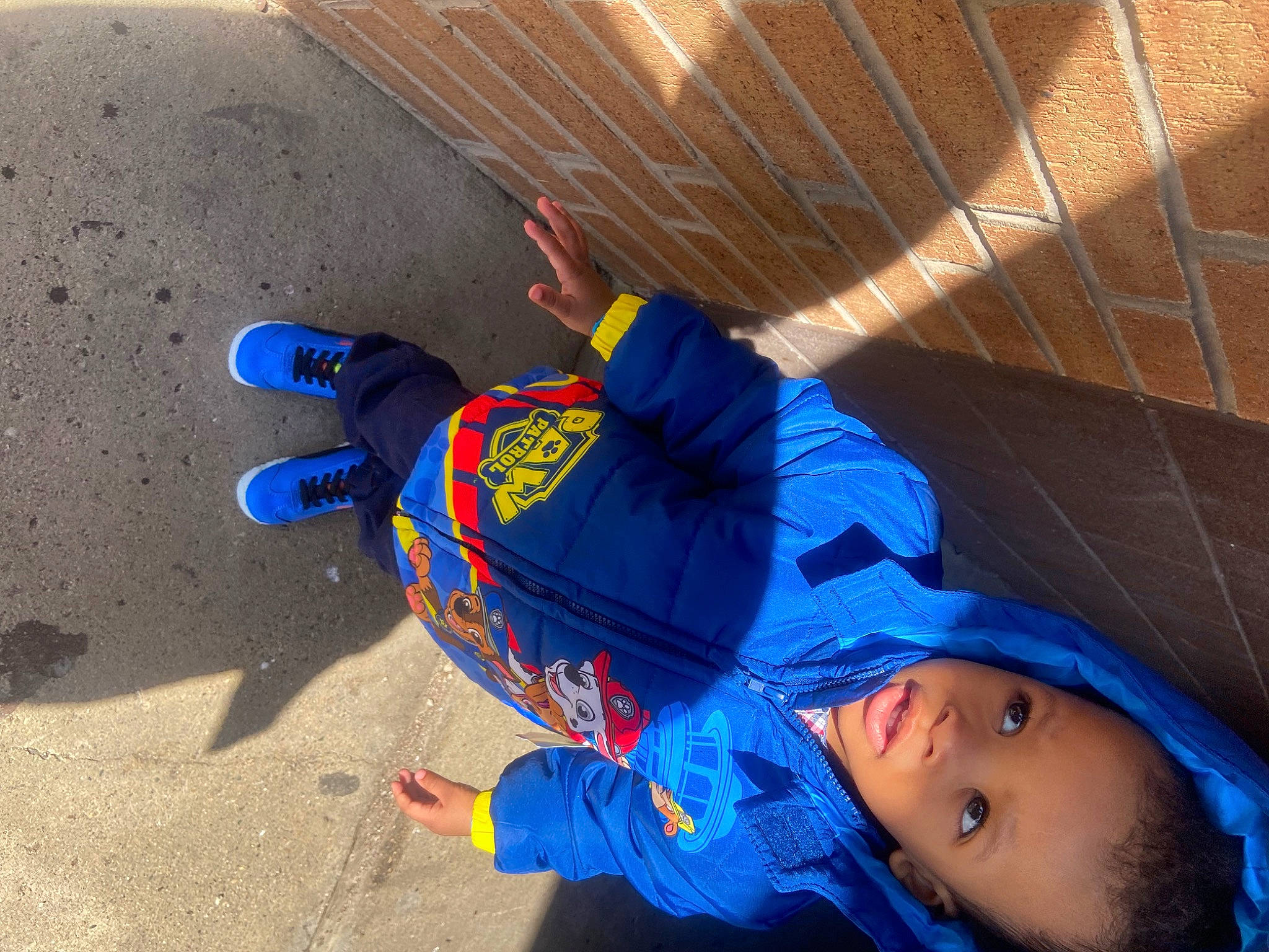 Kameron is registered to the contest to win money with this photo: asphalt, baseball_cap, child, concrete, electric_blue, flooring, fun, hat, landscape, leisure, person, play, recreation, shadow, sitting, soil, toddler, vacation, winter