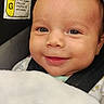baby, smiling, close_up, blanket, car_seat, face, infant, child, seatbelt, safety_label, portrait, cute, happy, indoors, skin, head, eyes, clothing, young_child, baby_boy