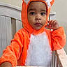 toddler, child, costume, fox, orange, white, crib, furniture, indoor, person, cute, portrait, expression, baby, clothing, headwear, hand, face, curious, young