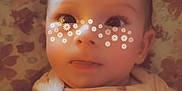 Charlotte is registered to the contest to win money with this photo: baby, infant, face, flower_filter, tongue, blanket, floral_pattern, cute, child, person, lying_down, soft_light, indoors, skin, head, eyes, cheeks, clothing, smile, expression