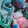 baby, sleeping, blanket, pillow, heart_pattern, indoor, cozy, infant, soft_fabric, colorful, rest, peaceful, child, face, head, person, comfort, nap, home, cushion