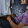 Donald a rejoint le concours — aidez-le/la à gagner de superbes lots ! elderly_woman, cat, indoor, glasses, floral_clothing, couch, curtains, plant, framed_artwork, wall_texture, tabby_cat, relaxing, comfort, hand, watch, home_interior, resting, pet, affection, seated