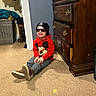 Dawson joined the competition — help win amazing prizes! child, smiling, sitting, indoor, carpet, hoodie, mickey_mouse, sunglasses, beanie, dresser, wooden_furniture, laundry_basket, clothing, happy, person, casual, floor, room, toy_character, fashion