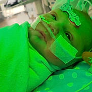 Harlee is registered to the contest to win money with this photo: baby, hospital, medical_tubes, blanket, face, infant, patient, bed, healthcare, nasal_cannula, tape, indoors, child, polka_dot, pillow, resting, monitoring, care, closeup, person