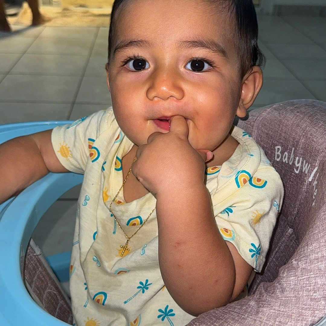 Aaron participe au concours pour gagner de l'argent avec cette photo : baby, big_eyes, child, clothing, cross_necklace, curly_hair, cute, expression, face, finger_in_mouth, gold_necklace, hand, high_chair, indoor, infant, person, portrait, sitting, tiled_floor, walker