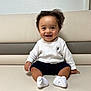 Seven participe au concours pour gagner de l'argent avec cette photo : toddler, baby, smiling, sitting, white_sweater, navy_shorts, couch, indoor, happy, child, face, hair, sock, cute, portrait, person, furniture, skin, expression, seated