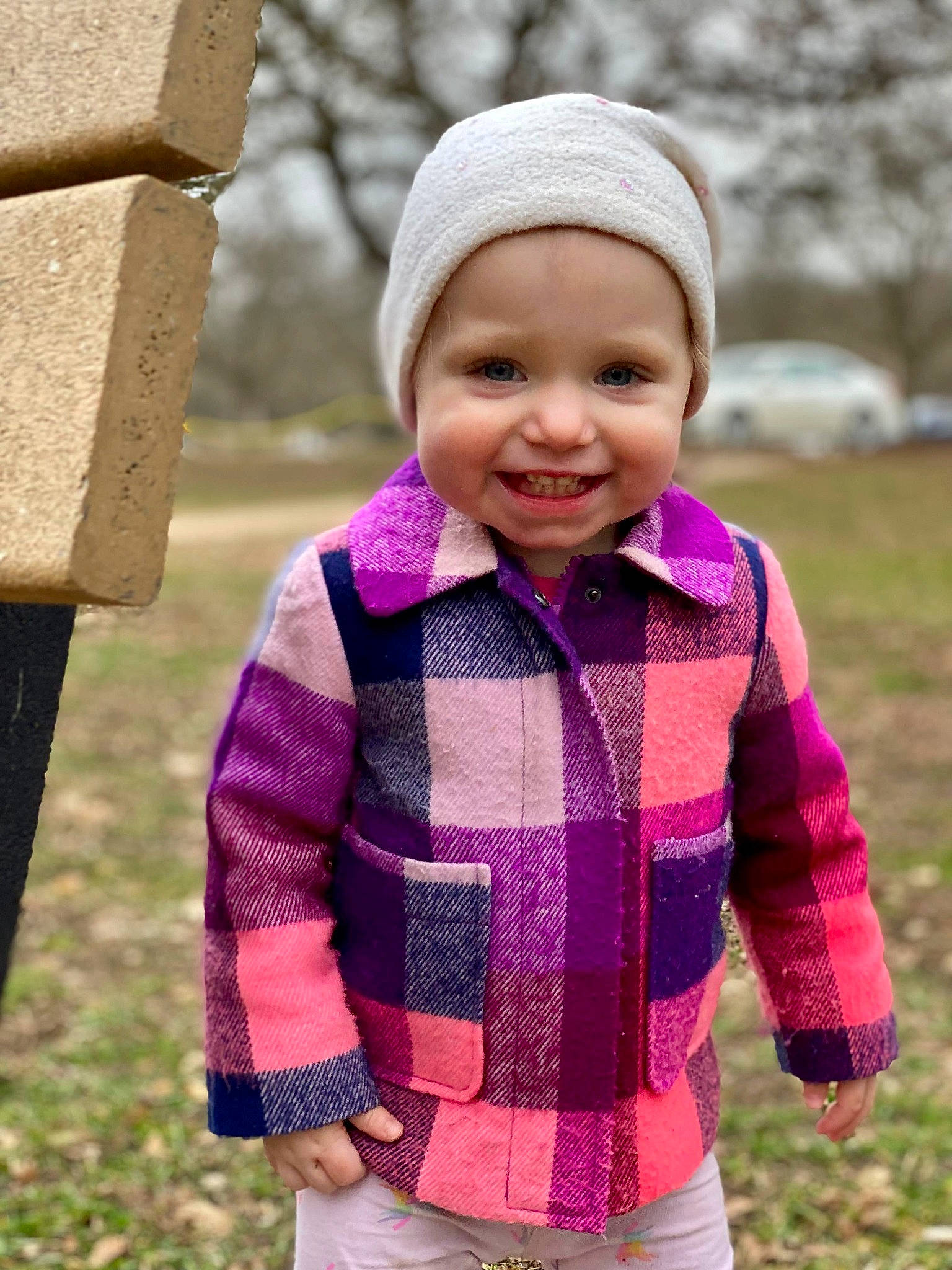 Gabriella is registered to the contest to win money with this photo: baby_toddler_clothing, cap, child, clothing, face, grass, happy, head, headgear, headwear, jacket, joy, magenta, pattern, people_in_nature, person, pink, plant, purple, sleeve