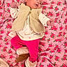 baby, infant, pink_blanket, floral_pattern, vest, boots, clothing, cute, portrait, lying_down, warm_clothes, indoor, cozy, child, person, footwear, fabric, soft, resting, casual