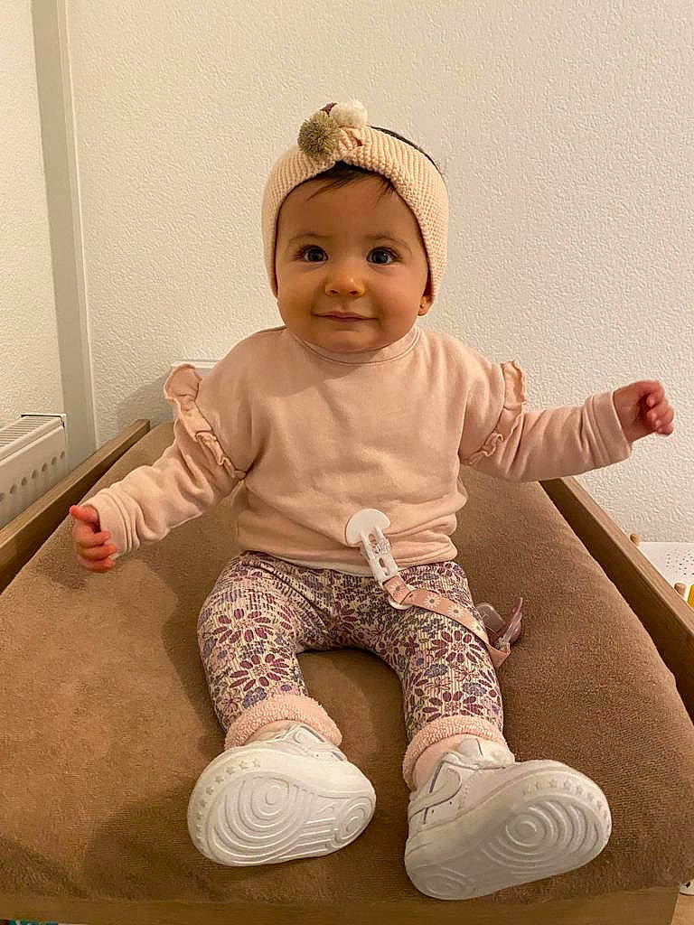 Khélya participe au concours pour gagner de l'argent avec cette photo : baby, baby_toddler_clothing, child, comfort, eye, fashion_accessory, foot, happy, headwear, human_leg, joy, knee, leg, pattern, person, pink, sitting, sleeve, smile, sock