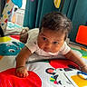 baby, infant, play_mat, colorful, toy, curly_hair, indoor, child, cute, reaching, white_clothing, bright_colors, floor_play, early_development, soft_toys, home, toddler, small_hand, focused, young_child
