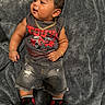 baby, child, infant, blanket, gray_blanket, clothing, tank_top, graphic_tshirt, ripped_shorts, denim_shorts, sneakers, nike, jewelry, gold_chain, bracelet, ring, footwear, cute, indoors, portrait