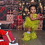 Willow is registered to the contest to win money with this photo: child, christmas_lights, christmas_tree, costume, decorations, festive, floor, fur, gift_boxes, green_outfit, holiday, indoors, leg_warmers, ornaments, pinecones, presents, red_outfit, santa_costume, toddler, wooden_floor