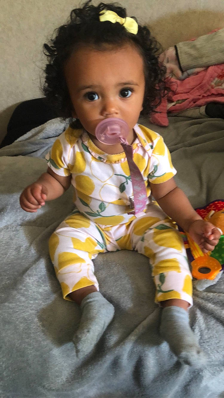 Sophia is registered to the contest to win money with this photo: baby, baby_toddler_clothing, cheek, child, comfort, face, finger, flooring, fun, hairstyle, happy, head, iris, lap, nose, person, sitting, skin, sleeve, sock