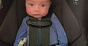Levi is registered to the contest to win money with this photo: baby, car_seat, child, infant, blue_clothing, mittens, socks, straps, seat_belt, safety, indoor, person, face, cute, newborn, looking, resting, small, pajamas, warning_label