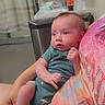 Levi joined the competition — help win amazing prizes! baby, infant, child, person, adult_hand, hospital, clinic, curtain, drink_cup, counter, sink, clothing, onesie, holding, indoor, skin, face, blue_eyes, pink_skin, seated