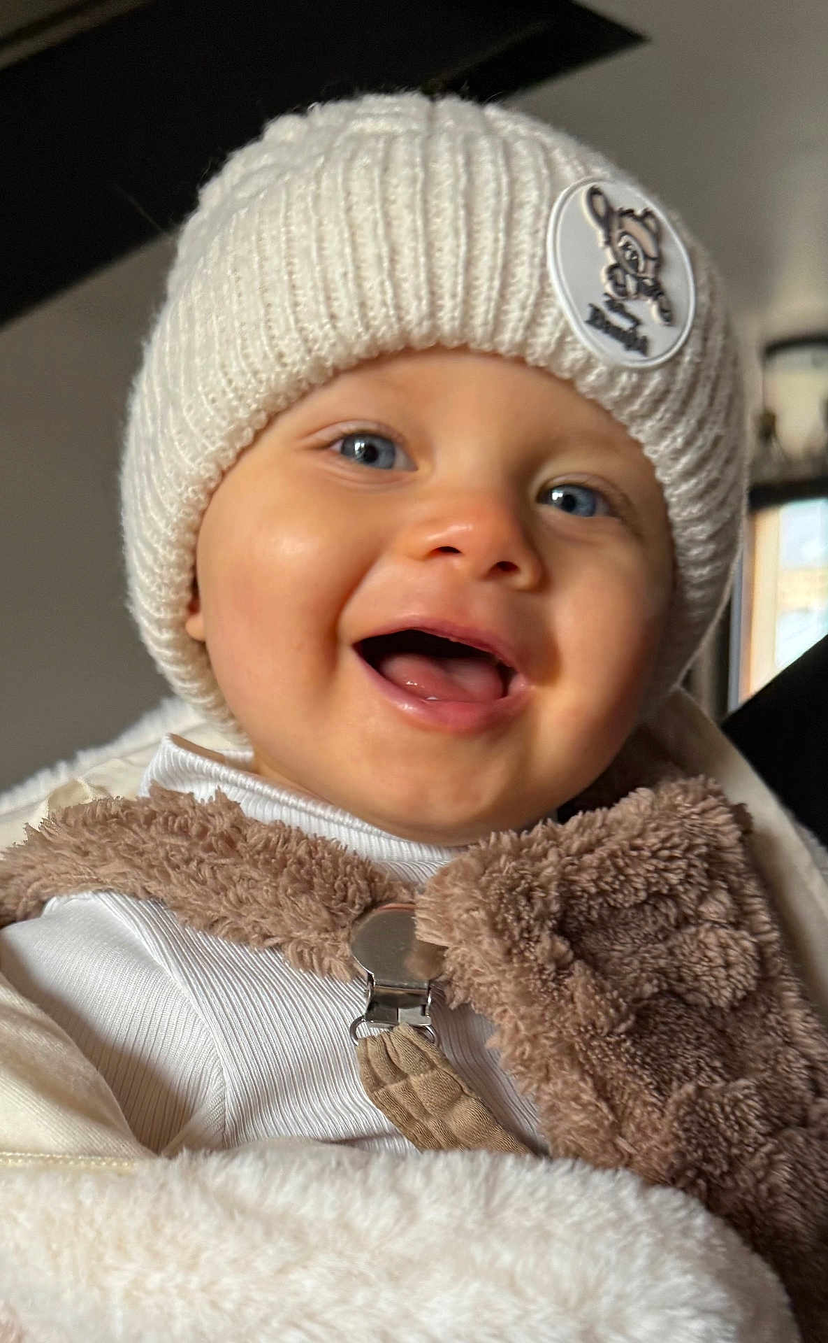 Talya a rejoint le concours — aidez-le/la à gagner de superbes lots ! baby, child, smiling, hat, knitted_hat, blue_eyes, scarf, brown_scarf, blanket, white_clothing, indoor, portrait, face, happy, cute, warm_clothing, winter_wear, cozy, closeup, person