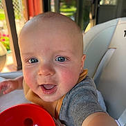 Enzo is registered to the contest to win money with this photo: baby, child, face, blue_eyes, smiling, rosy_cheeks, indoor, high_chair, toy, red, selfie, cute, happy, person, closeup, infant, casual_clothing, daylight, expression, reaching_hand