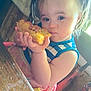 Athena is registered to the contest to win money with this photo: toddler, child, food, pigtails, high_chair, table, wooden_table, chair, face, hands, messy, eating, indoor, window_light, blue_clothing, pink_clothing, person, portrait, serious_expression, meal