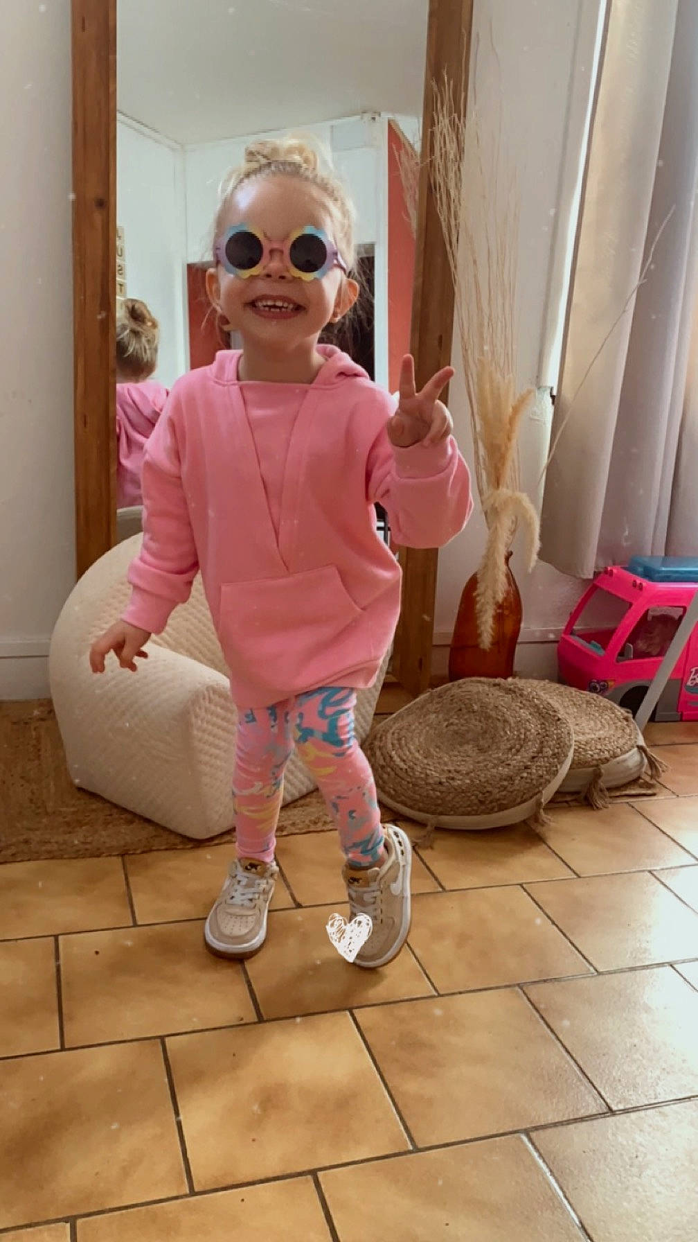 Ema participe au concours pour gagner de l'argent avec cette photo : baby_toddler_clothing, child, curtain, eyewear, floor, flooring, fun, goggles, hardwood, human_leg, joy, magenta, person, pink, shoe, smile, sunglasses, toddler, toy, vacation