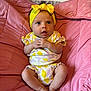 Celine is registered to the contest to win money with this photo: baby, infant, child, headband, yellow, pink, cushion, clothing, sitting, barefoot, cute, expression, indoors, portrait, small_hands, legs, feet, fabric, comfortable, curious