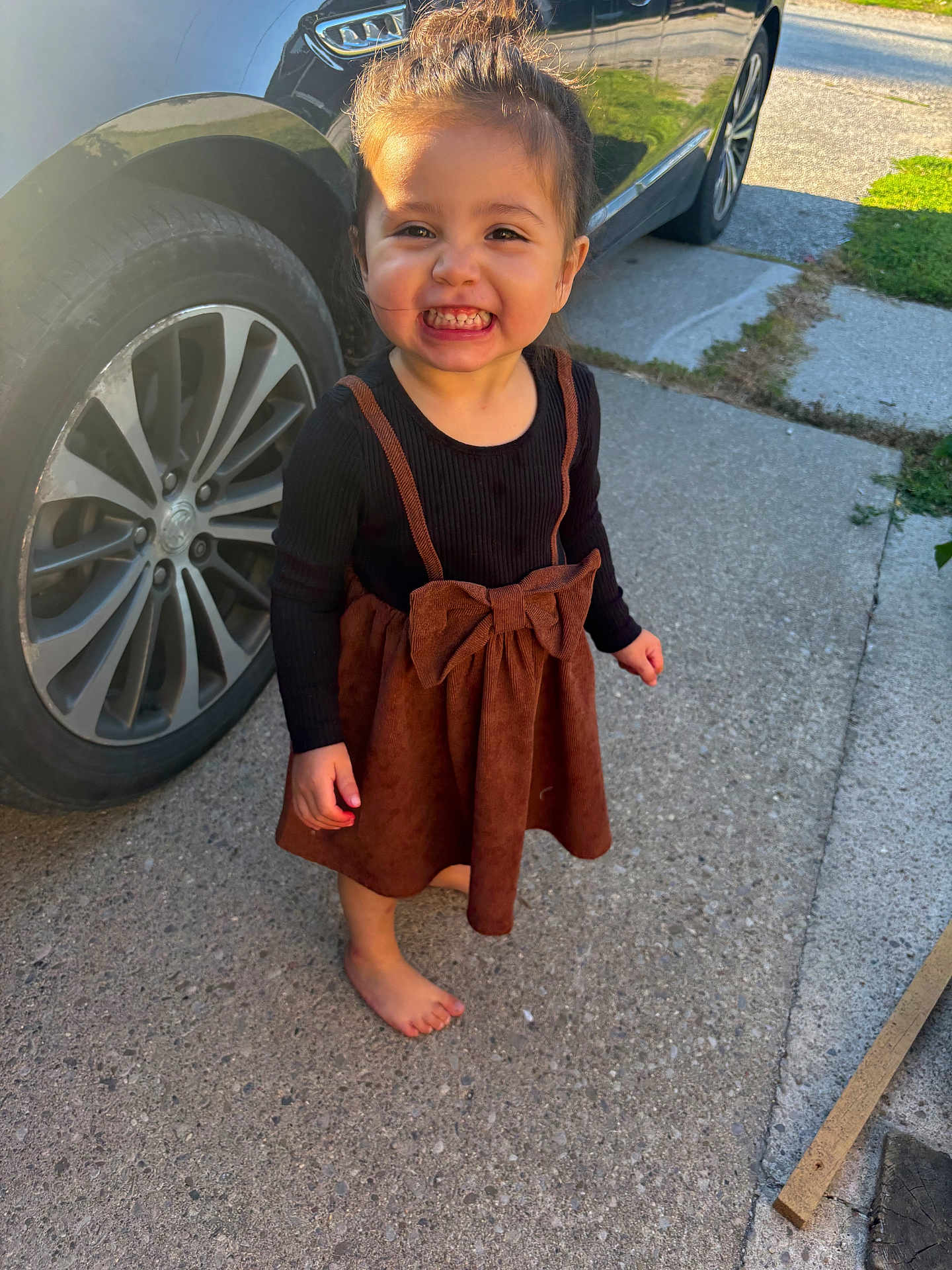 Nevaeh is registered to the contest to win money with this photo: toddler, child, smiling, barefoot, dress, bow, car, wheel, concrete, outdoor, sunlight, happy, person, clothing, sidewalk, grass, daylight, cute, young, standing