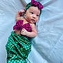 baby, infant, mermaid_costume, green, purple, sequin, headband, bow, lying_down, white_background, cute, small_hand, face, skin, expression, child, costume, fabric, soft, portrait