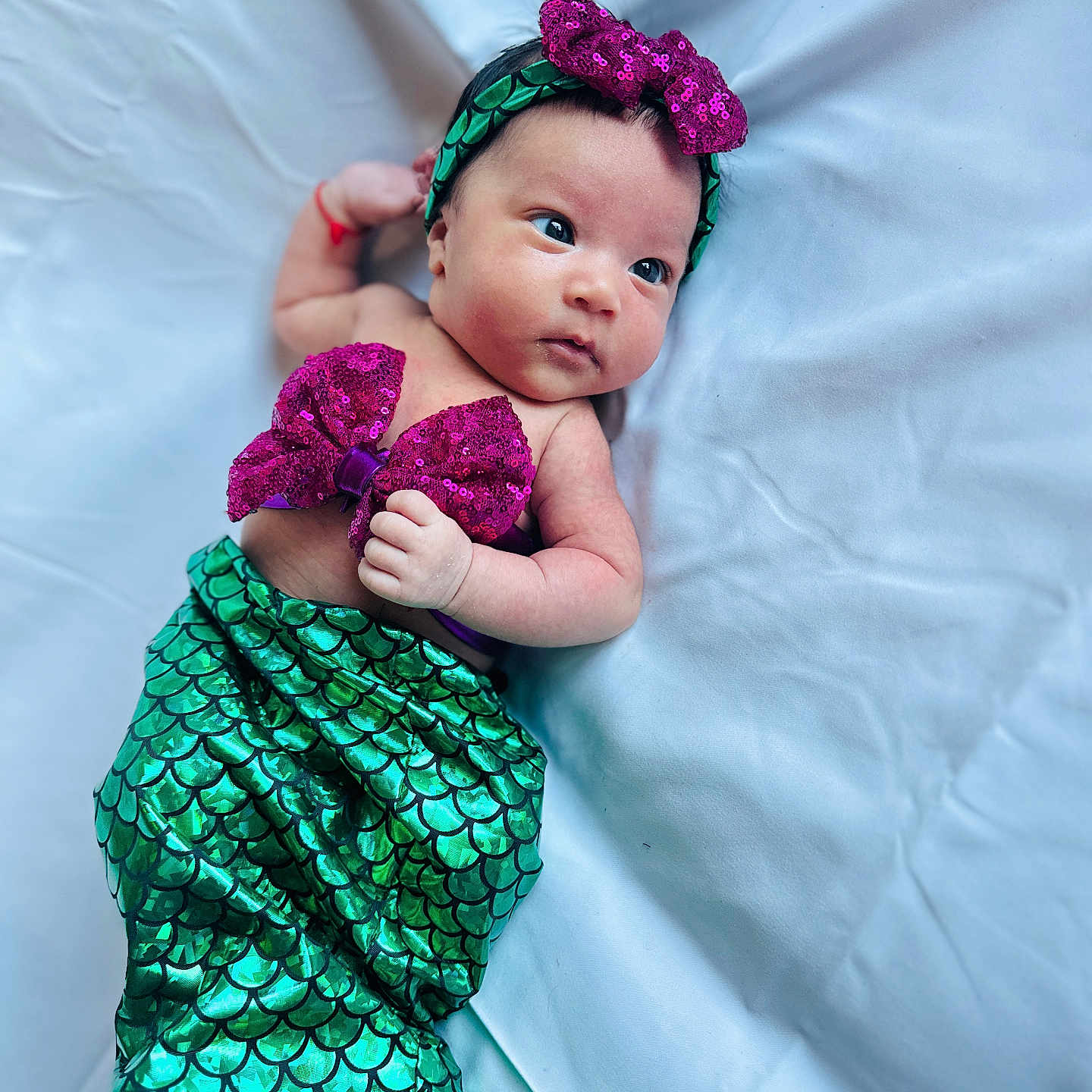 Samragi joined the competition — help win amazing prizes! baby, bow, child, costume, cute, expression, fabric, face, green, headband, infant, lying_down, mermaid_costume, portrait, purple, sequin, skin, small_hand, soft, white_background