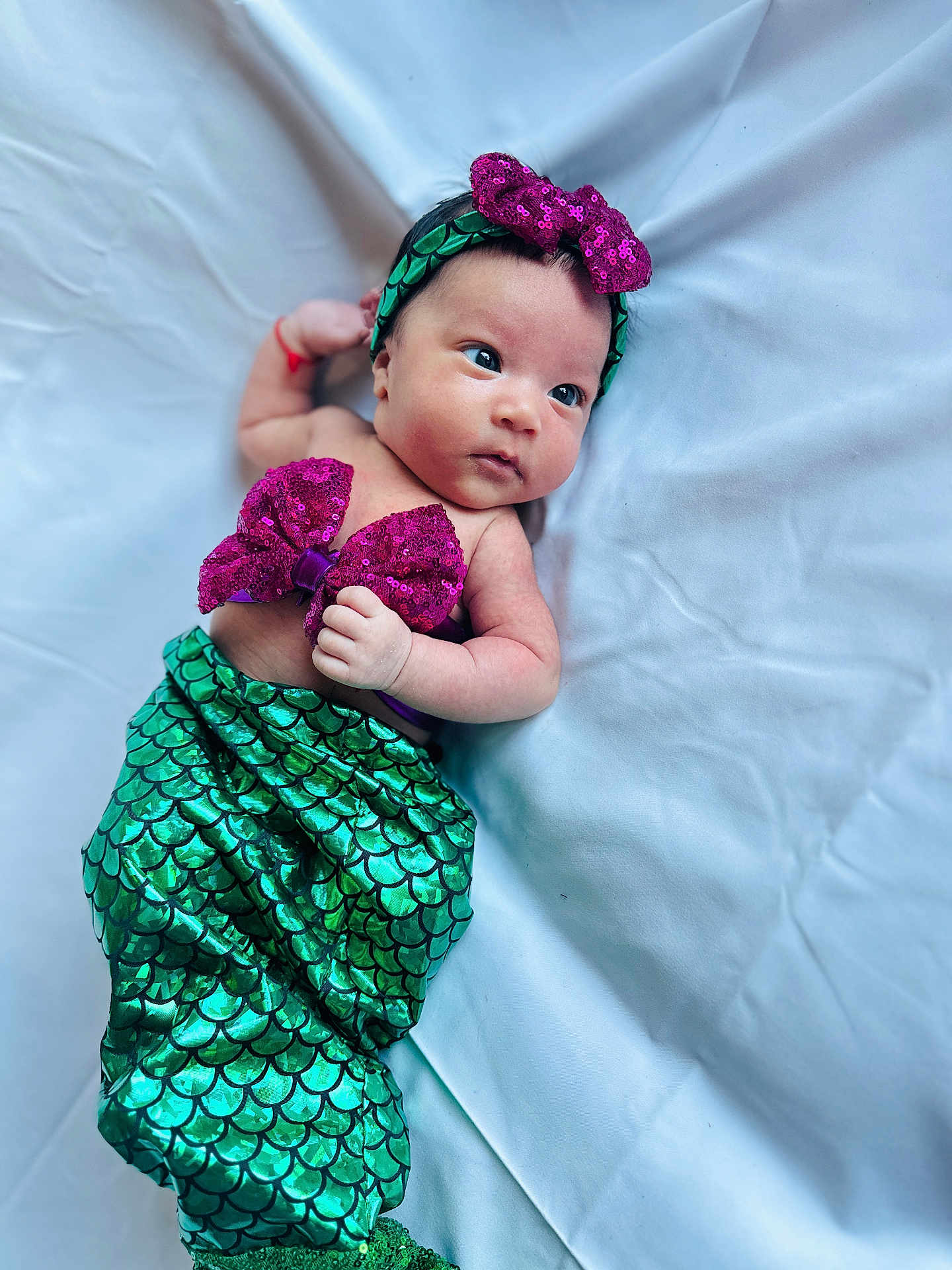 Samragi joined the competition — help win amazing prizes! baby, infant, mermaid_costume, green, purple, sequin, headband, bow, lying_down, white_background, cute, small_hand, face, skin, expression, child, costume, fabric, soft, portrait