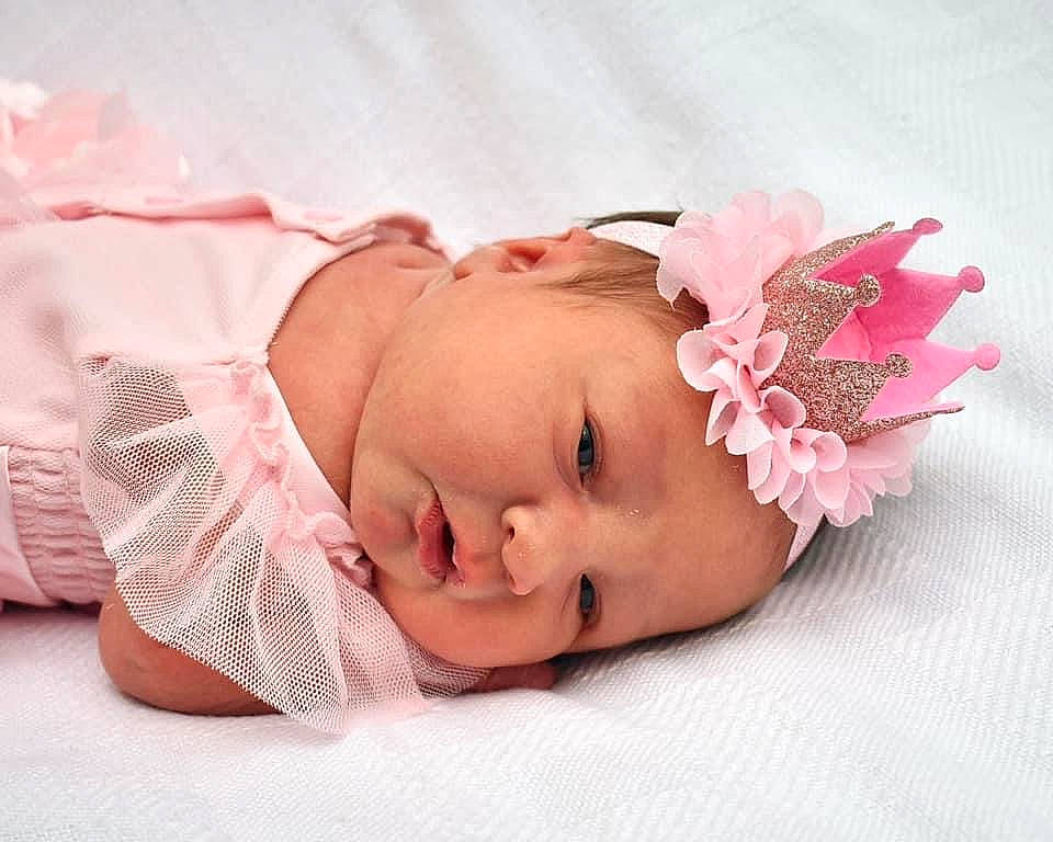 Holly is registered to the contest to win money with this photo: baby, baby_toddler_clothing, cheek, child, comfort, eyelash, fashion_accessory, flower, hair_accessory, headband, headgear, headpiece, headwear, lip, pattern, person, petal, pink, skin, sleeve