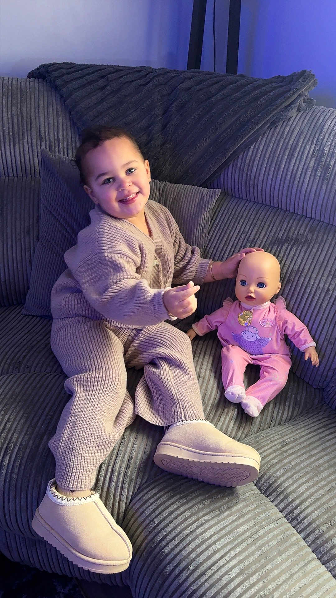 Alaya-Jay joined the competition — help win amazing prizes! child, toddler, doll, couch, knitwear, slippers, indoor, plush, smile, happy, cozy, baby_doll, pink_clothing, furniture, portrait, seated, playful, home, soft_lighting, corduroy