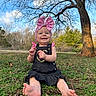 baby, child, smiling, outdoor, grass, tree, sky, cloud, bare_tree, headband, pink_bow, dress, barefoot, nature, greenery, sunlight, portrait, happy, sitting, infant