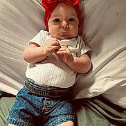 Scarlett joined the competition — help win amazing prizes! baby, infant, child, red_bow, headband, white_shirt, denim_shorts, bed, pillow, blanket, hands, face, looking_at_camera, indoors, cute, lying_down, skin, expression, wide_eyes, clothing