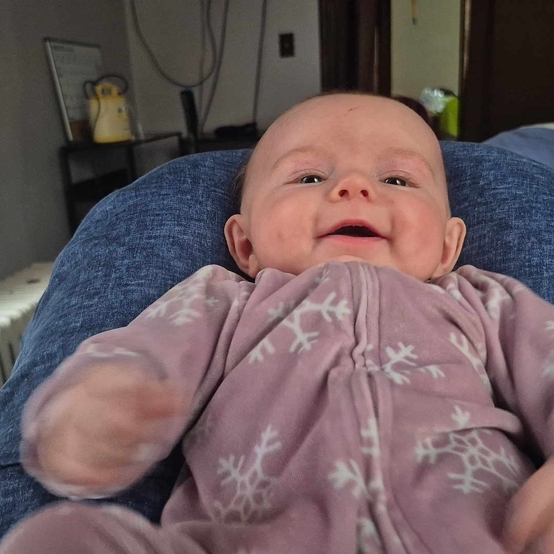 Annalee joined the competition — help win amazing prizes! baby, casual, child, cozy, cute, face, furniture, happy, head, home, indoor, infant, legs, onesie, person, pink_clothing, portrait, radiator, smiling, snowflake_pattern