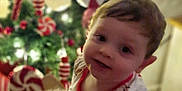 Freddie is registered to the contest to win money with this photo: child, toddler, pajamas, toy, rocking_horse, plush_toy, christmas_tree, ornaments, peppermint, holiday, festive, indoor, smiling, cute, decorations, holiday_lights, face, person, celebration, seasonal