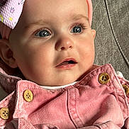 Maddison is registered to the contest to win money with this photo: baby, child, infant, face, blue_eyes, headband, bow, pink_clothing, buttons, close_up, portrait, curious_expression, soft_lighting, fabric_background, candid, cute, young_child, indoor, skin, person