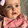 baby, child, infant, face, blue_eyes, headband, bow, pink_clothing, buttons, close_up, portrait, curious_expression, soft_lighting, fabric_background, candid, cute, young_child, indoor, skin, person