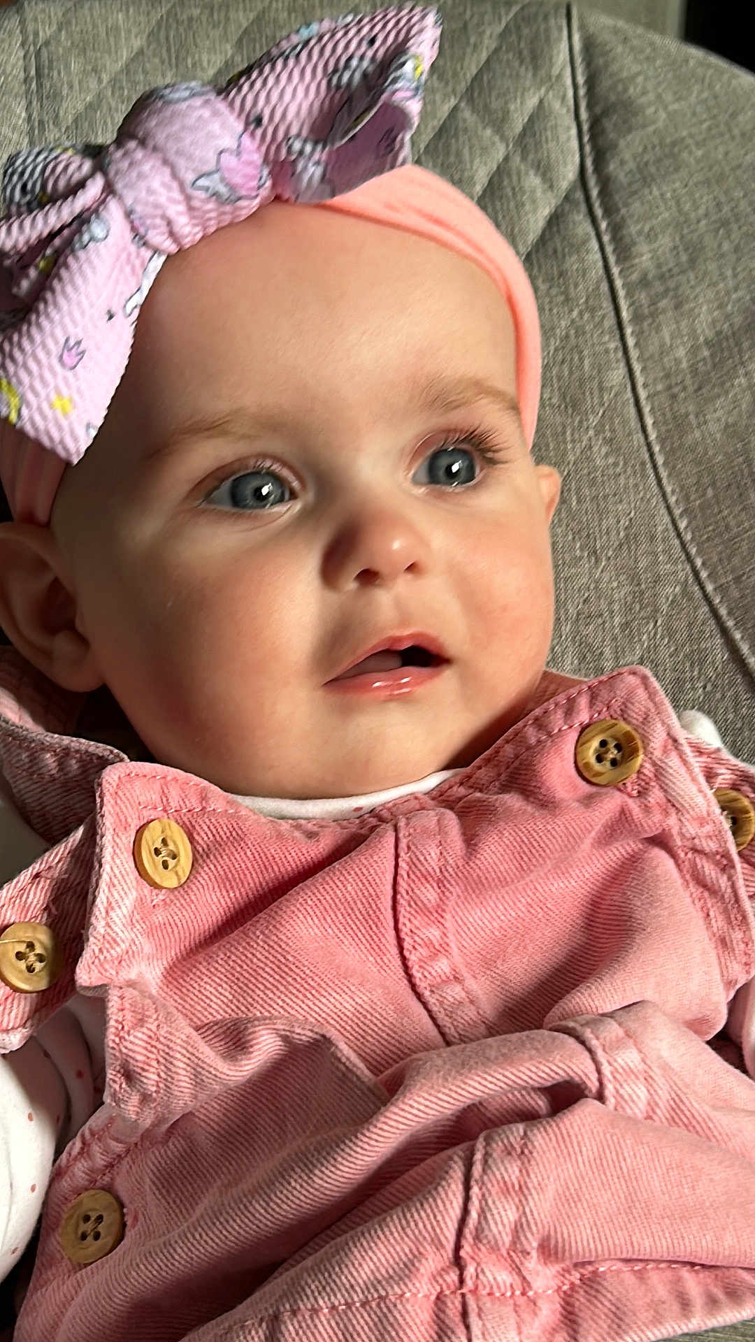 Maddison is registered to the contest to win money with this photo: baby, child, infant, face, blue_eyes, headband, bow, pink_clothing, buttons, close_up, portrait, curious_expression, soft_lighting, fabric_background, candid, cute, young_child, indoor, skin, person