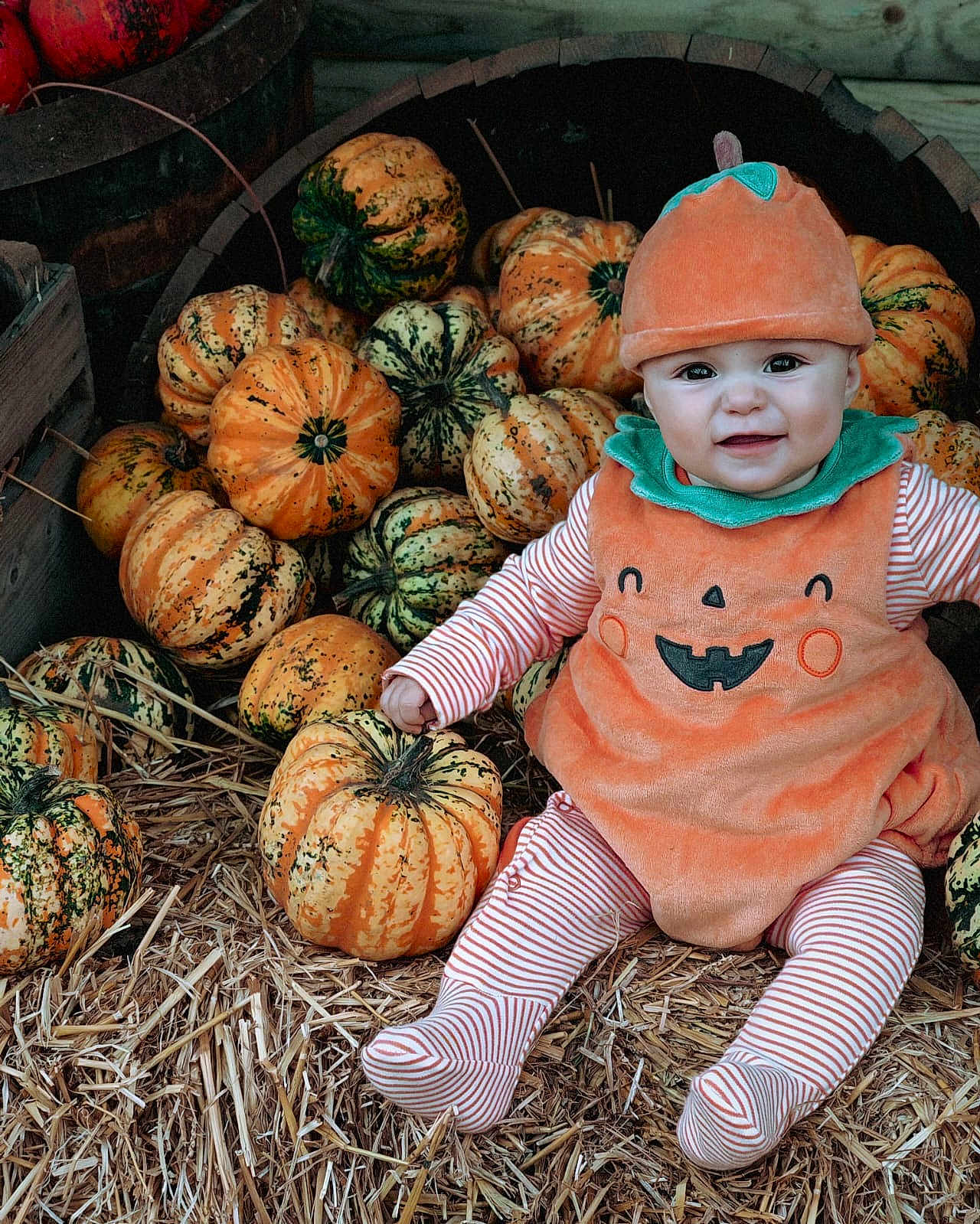 Alessia is registered to the contest to win money with this photo: baby, child, pumpkin_costume, pumpkins, straw, autumn, orange, hat, smile, face, striped_clothing, festive, seasonal, cute, sitting, outdoor, harvest, holiday, person, fun