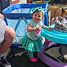 toddler, child, playpen, outdoor, dog, playground, table, headband, smiling, green_clothing, sunny, fence, person, toy, footwear, happy, grass, daylight, baby, backyard