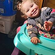 Calista is registered to the contest to win money with this photo: baby_walker, bucket, child, colorful, curly_hair, cute, flooring, happy, household_items, indoor, person, pigtails, plastic, playful, portrait, sitting, smiling, sweatshirt, toddler, young_child