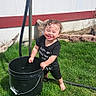 Calista is registered to the contest to win money with this photo: barefoot, black_bucket, child, clothing, curly_hair, daytime, garden_hose, grass, happy, house, outdoor, playful, red_trim, shorts, smiling, sunny, toddler, wall, water, window
